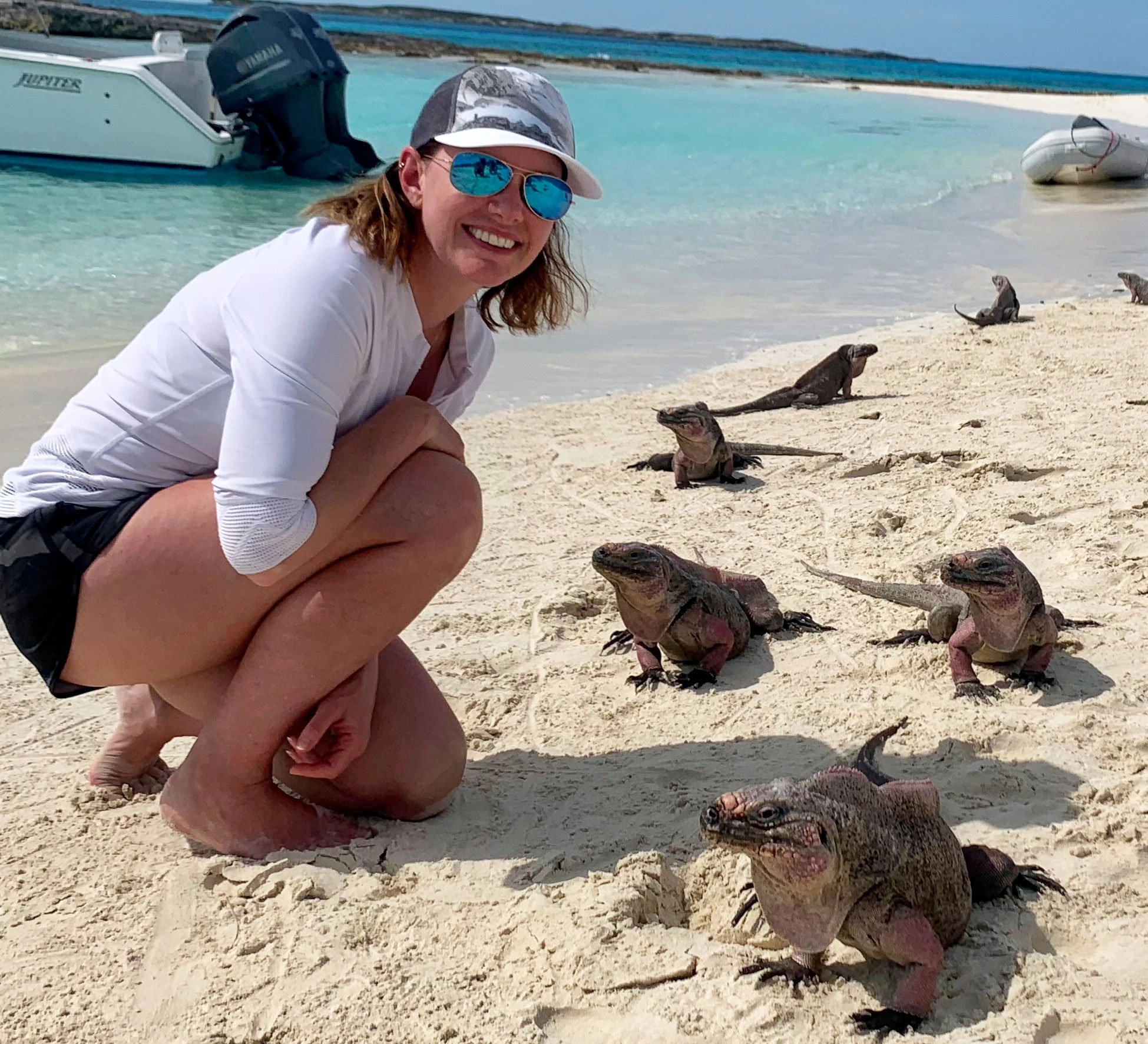 iguana-portrait Woman crousching alongside pink iguanas
